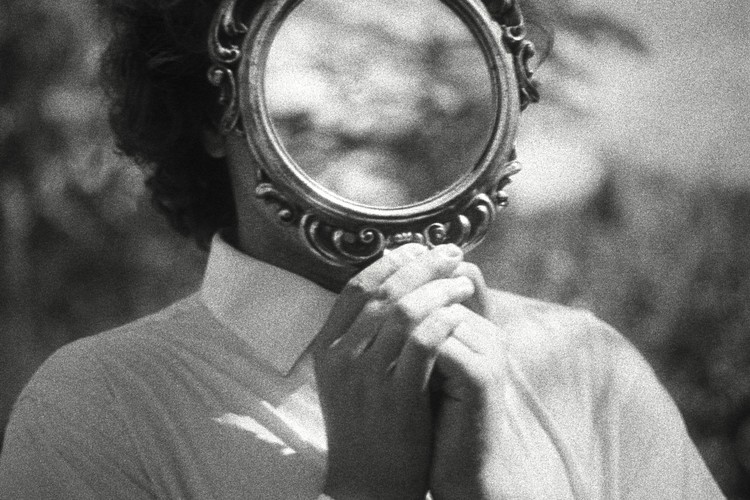 Aynaya bakan düşünceli kişi; içgörü ve farkındalığı sembolize eder.